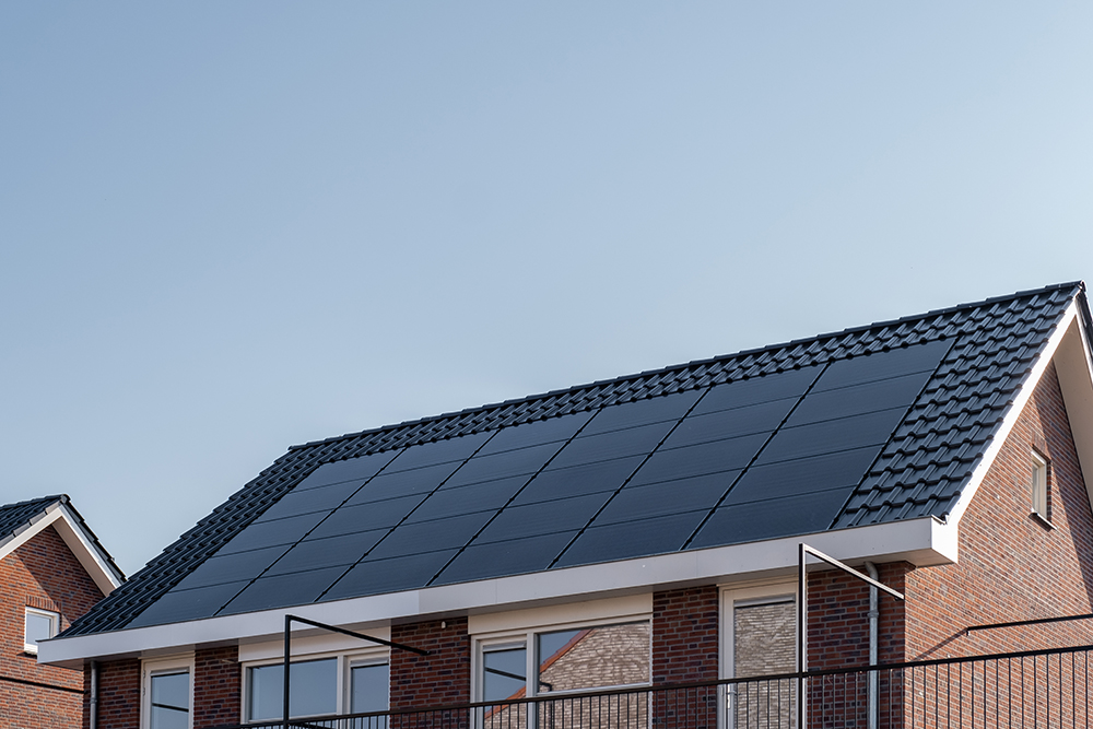 Newly build houses with solar panels attached on the roof against a sunny sky Close up of new building with black solar panels. Zonnepanelen, Zonne energie, Translation: Solar panel, , Sun Energy. Netherlands