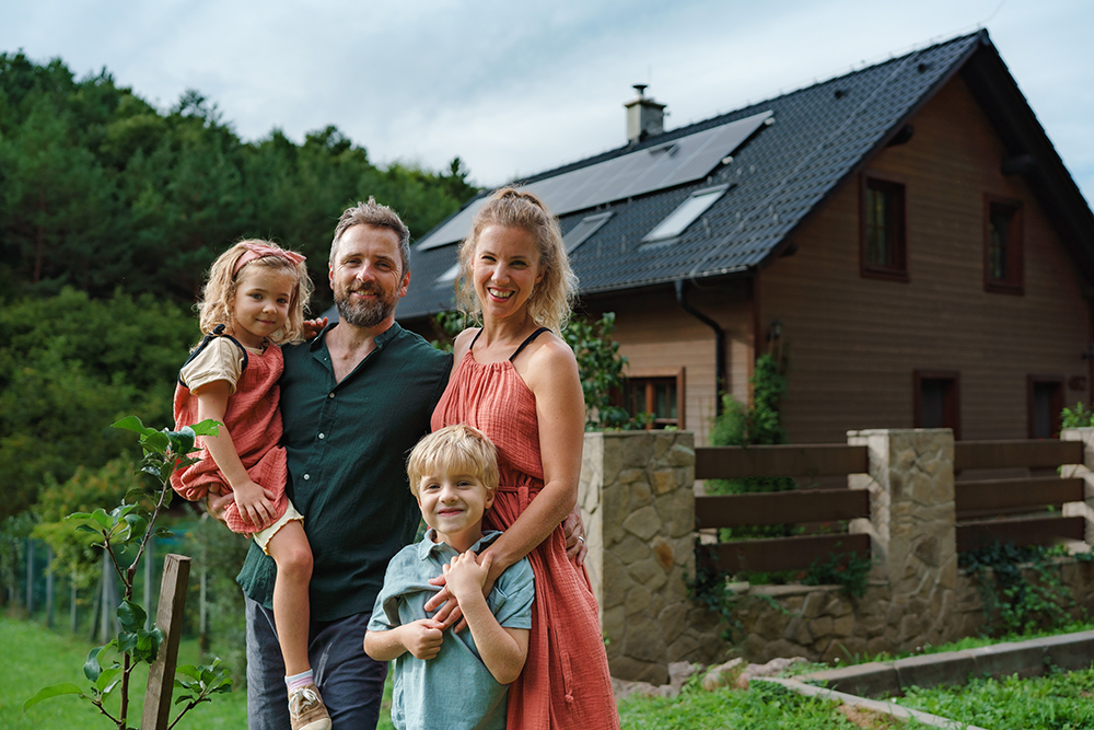 Happy family near their house with a solar panels. Alternative energy, saving resources and sustainable lifestyle concept.